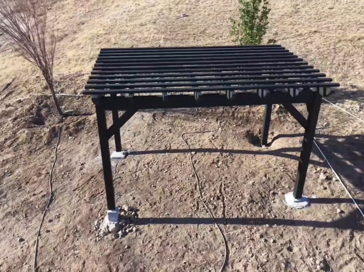A Slate-stained 12 by 16 foot timber pergola with straight knee braces and a lattice top on a hillside lot in Lehi, Utah