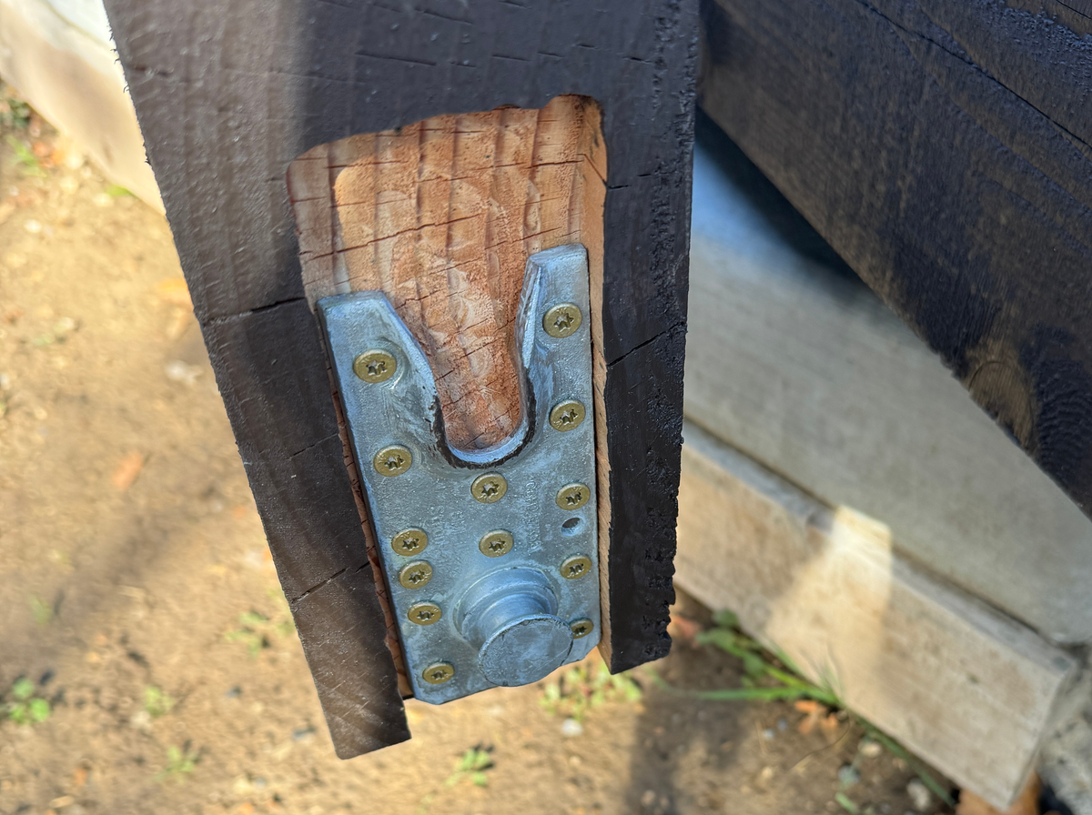 A galvanized steel beam bracket screwed into a pocket cut in the top of a Cordovan Brown post before it goes up, Elk Ridge, Utah